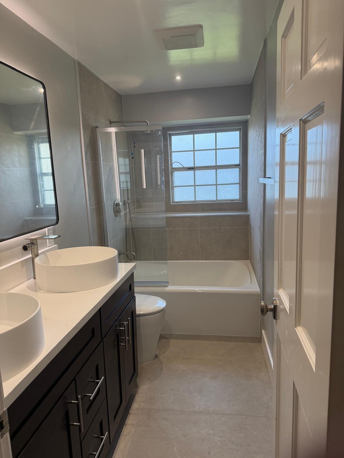 After: modern Anaheim guest bathroom with gray porcelain and frameless glass