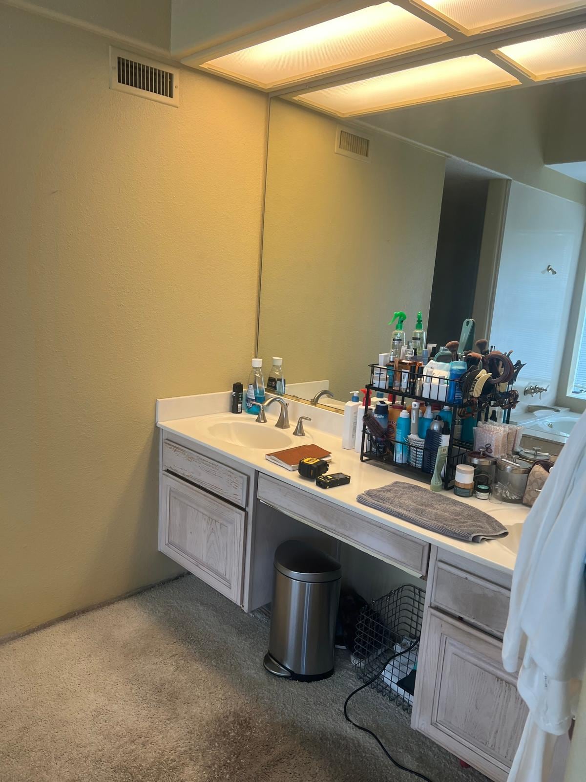 Before: dated Mission Viejo primary bathroom vanity with pickled-oak cabinets, cultured-marble top, and carpet
